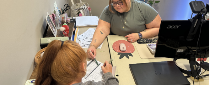 A young Latina JFS professional helps a female client review a family budget.