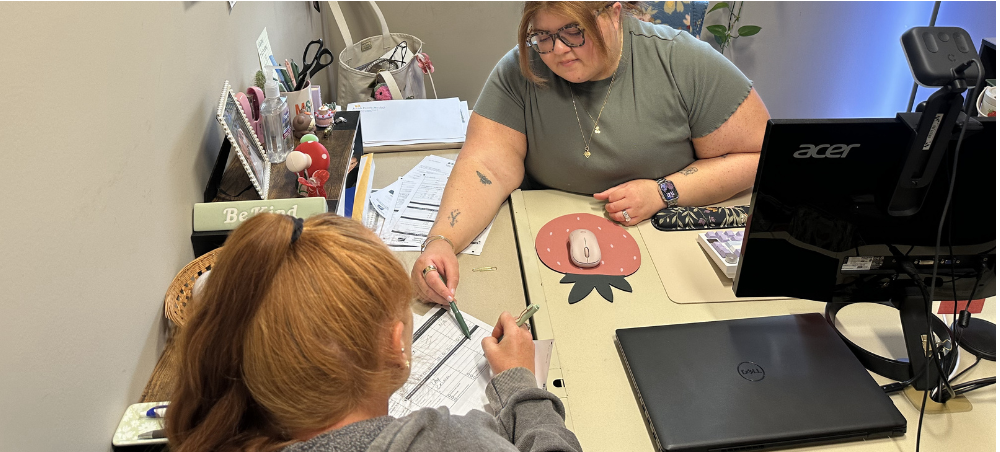 Alicia H and client A young Latina JFS professional helps a female client review a family budget.