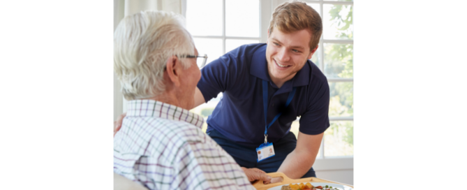 A young caregiver brings a meal to an elderly man.